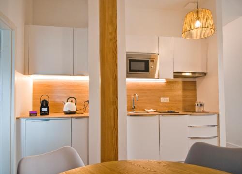 une cuisine avec des armoires blanches, une table et un micro-ondes dans l'établissement CosyBNB bleu, logement indépendant, wifi, parking, petit déjeuner, à Ittenheim