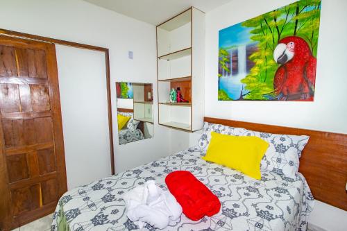 a bedroom with a bed with a red pillow and a parrot painting at Casa da Joana in Morro de São Paulo
