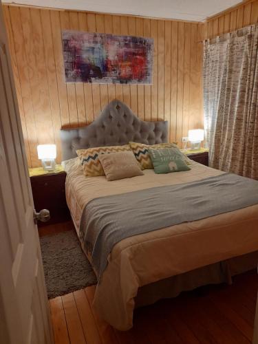 a bedroom with a bed with two lamps and two tables at Descanso Sureño Hospedaje in Valdivia