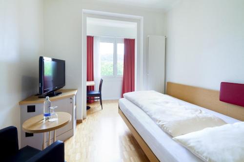 a hotel room with a bed and a flat screen tv at Swiss Star Irchel - Self Check-In in Zurich