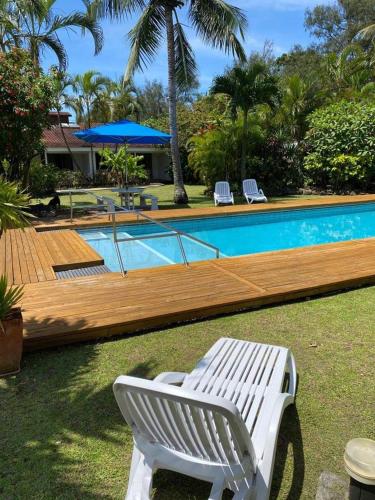 a white bench sitting next to a swimming pool at The Black Pearl Beachside Apartments in Rarotonga