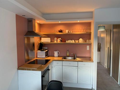 La cuisine est équipée de placards blancs, d'un évier et d'étagères. dans l'établissement Gite les montgolfières, à Wimereux