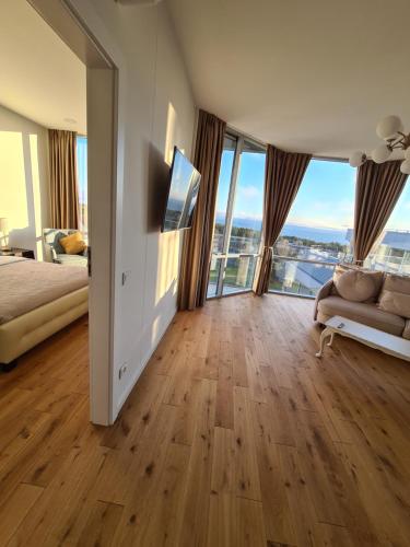 a bedroom with a bed and a couch and windows at Sea View Apartment Elija in Šventoji
