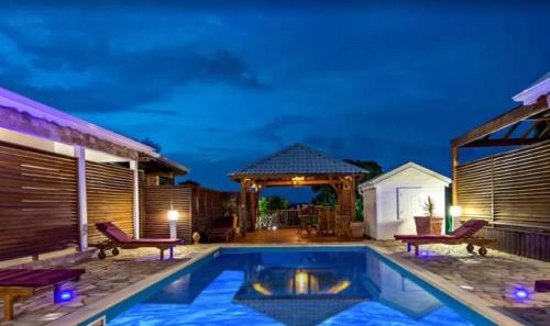 a swimming pool with two chairs and a gazebo at Maison cosy avec jardin à Anse-Bertrand in Anse-Bertrand