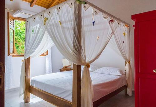a bedroom with a canopy bed with white curtains at Maison cosy avec jardin à Anse-Bertrand in Anse-Bertrand