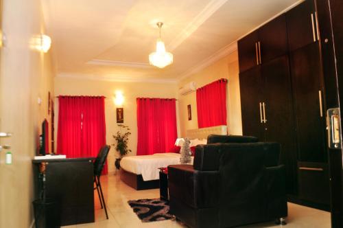 a bedroom with red curtains and a bed and a couch at J Gibson Hotel in Lagos