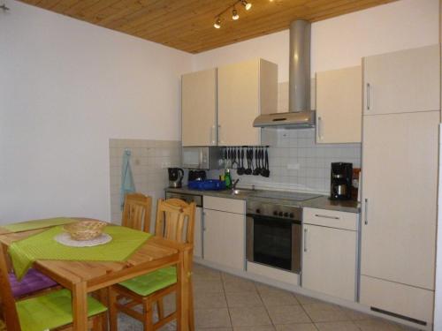 a kitchen with white cabinets and a table and chairs at Herrenhaus Poppelvitz in Maltzien