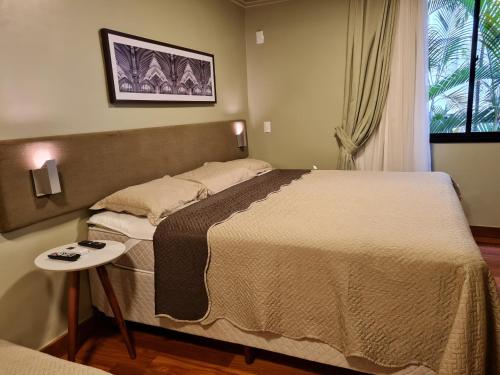 1 dormitorio con 1 cama grande y 1 mesa en (109)Flat Poeta Drummond Jardins (Apt Particular), en São Paulo