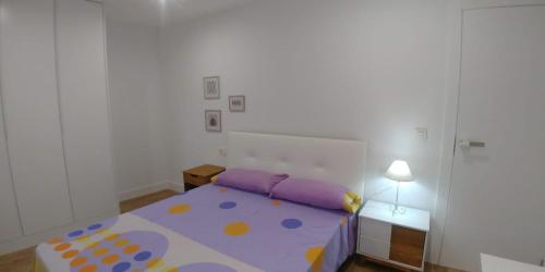 sypialnia z fioletowym łóżkiem i białą ścianą w obiekcie Cómodo apartamento en zona antigua dos w mieście Pontevedra