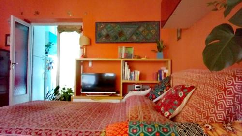 um quarto com paredes cor-de-laranja, uma cama e uma televisão. em 4321 B&B Stazione Trastevere em Roma
