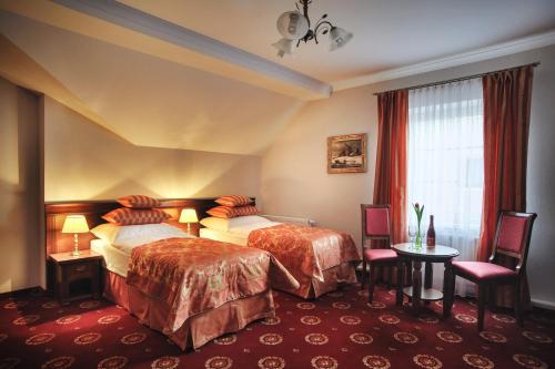 a hotel room with two beds and a table and chairs at Hotel Kopernik in Ciechocinek