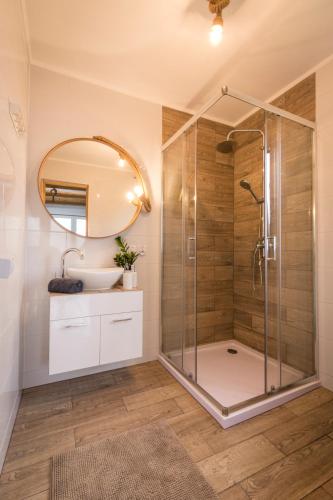 a bathroom with a shower and a sink and a mirror at Domki na Łazach in Uherce Mineralne (7)