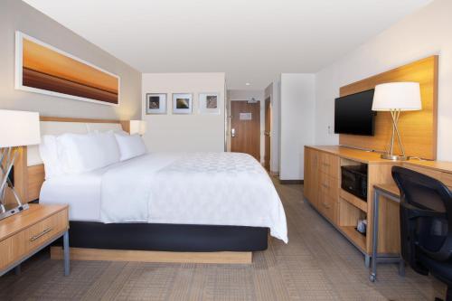 a hotel room with a bed and a flat screen tv at Holiday Inn Morgantown-University Area by IHG in Morgantown
