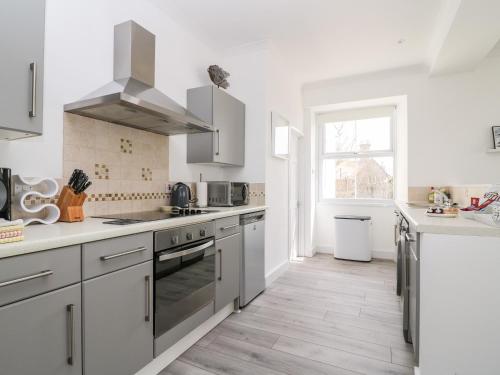 a kitchen with white cabinets and stainless steel appliances at Sea Breeze in Marazion