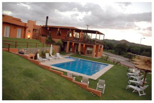 a house with a swimming pool in front of a building at Hotel Posada Terrazas con pileta climatizada in Potrero de los Funes