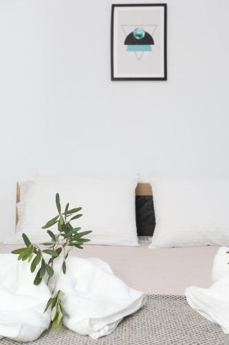 a white bedroom with white pillows and a plant at Mare Monte Luxury Apartments 2 in Nea Skioni