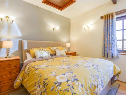 a bedroom with a bed with a yellow comforter at Miners Dry in Gunnislake