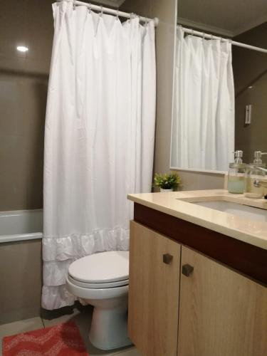 a bathroom with a toilet and a white shower curtain at Depto 1 Dormitorio 1504 Central con estacionamiento in Temuco