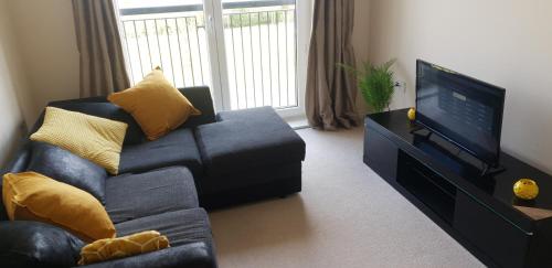 a living room with a couch and a flat screen tv at Hobart Apartment Chelmsford in Chelmsford