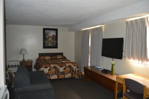 a hotel room with a bed and a flat screen tv at Wheel Inn Motel in Assiniboia