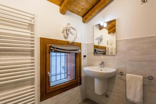 une salle de bain avec un lavabo et un miroir dans l'établissement COTTAGE GIULIA, à Argegno