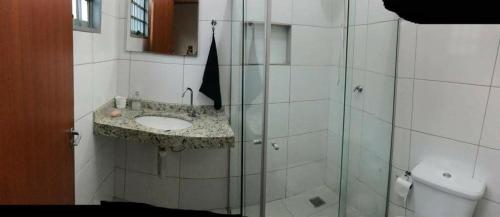 uma casa de banho com um lavatório e uma cabina de duche em vidro. em Casa - Chácara Bella Arraes em Bauru