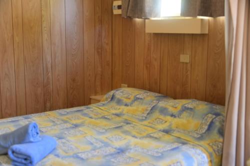a bedroom with a bed with a blue towel on it at Ball Park Caravan Park in Corowa