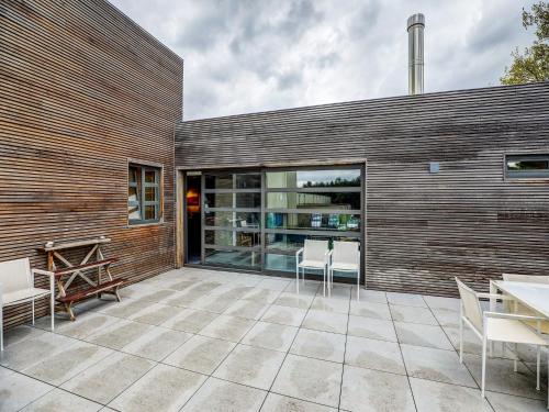 un patio con sillas blancas y una pared de madera en Classy Apartment in Weelde with Swimming Pool, en Weelde