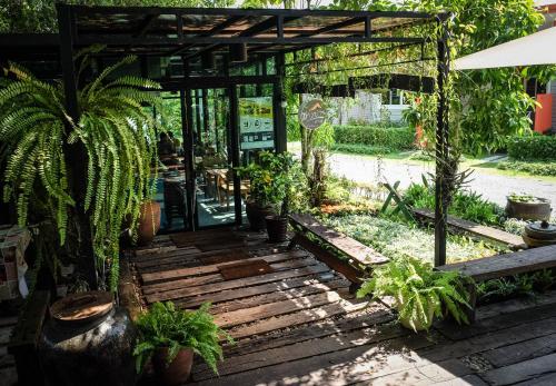 un jardín con plantas y un patio de madera en โรงแรมบ้านเพิ่มสุข อิมแพ็ค เมืองทอง, en Pak Kret