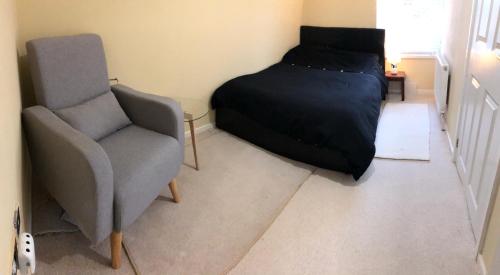 een slaapkamer met een bed en een stoel bij Private Double Room With New En-suite Shower Room in Kings Lynn