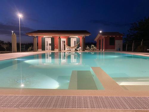 a large swimming pool in front of a house at night at Verde Oliva Residence in Ispica
