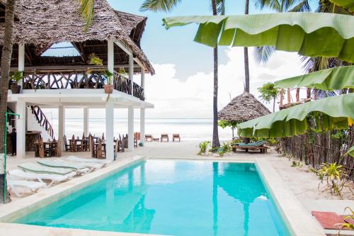 una piscina en un complejo de playa con sillas y sombrillas en Maisha Matamu Beach Hotel Paje, en Paje