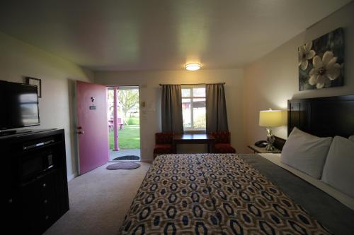 een slaapkamer met een groot bed en een televisie bij Mariners Cove Inn in Westport