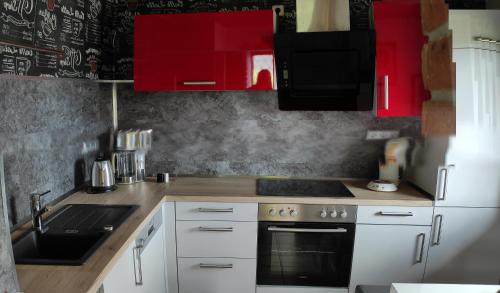 a kitchen with white appliances and red cabinets at Ferienhaus im Ederbergland in Hatzfeld
