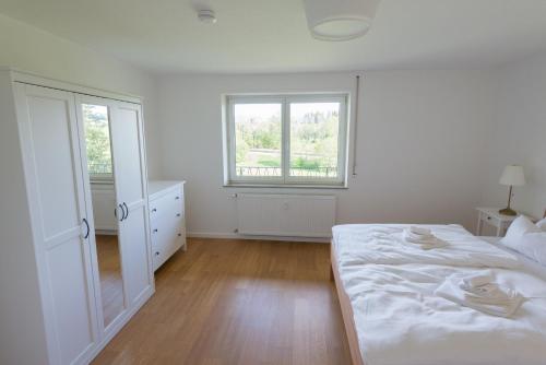 a white bedroom with a bed and a window at Gästehaus Albero in Lindau
