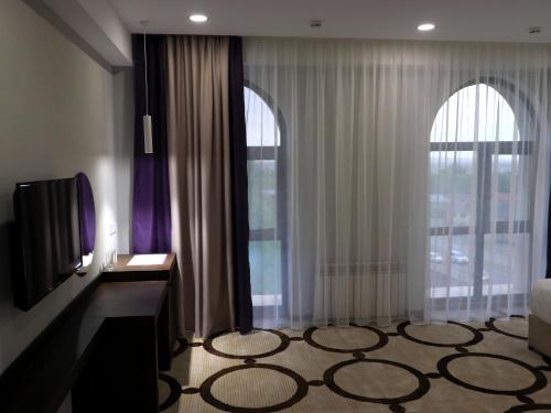 a living room with two large windows and a television at East Palace Hotel in Almaty