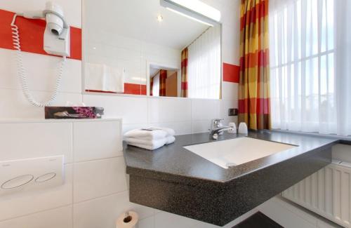 a bathroom with a sink and a mirror at Hotel Restaurant Thum in Balingen