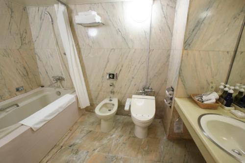 ein Badezimmer mit einem WC, einer Badewanne und einem Waschbecken in der Unterkunft Koyo Grand Hotel in Sendai