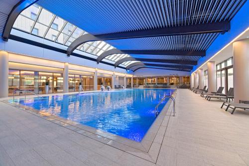 a large indoor swimming pool with a blue ceiling at Ramada Plaza by Wyndham Bucharest Convention Center in Bucharest