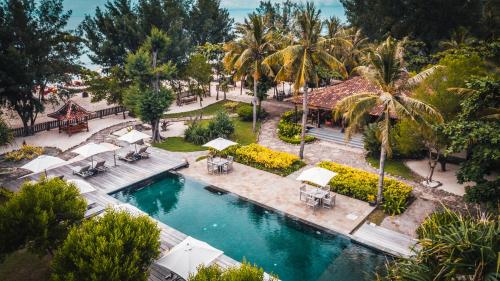 an aerial view of a pool with umbrellas and palm trees at Desa Dunia Beda Resort in Gili Trawangan