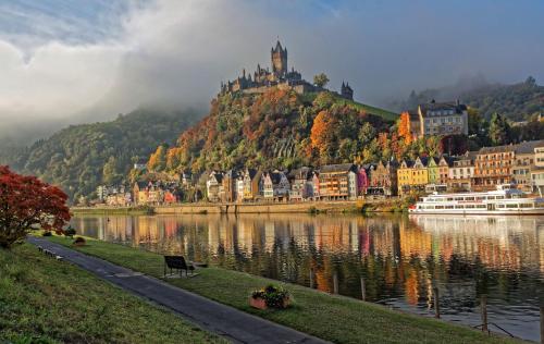 a city with a castle on a hill next to a lake at Komfort Ferienwohnung FEWO74-2 in Bremm