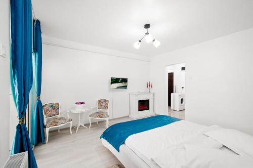 ein weißes Schlafzimmer mit einem Bett, einem Tisch und Stühlen in der Unterkunft Blue Studio in Galaţi