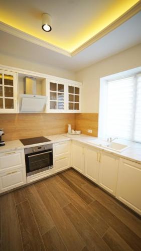 kuchnia z białymi szafkami, umywalką i oknem w obiekcie City apartments T w mieście Satu Mare