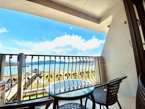 a balcony with a table and chairs and a view of the beach at Ming Yue Hu Hotel in Yuchi
