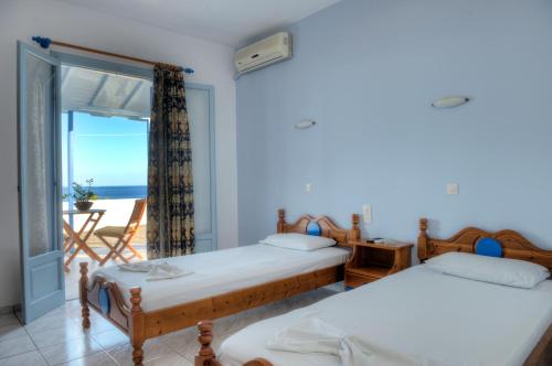 two beds in a room with a view of the ocean at Kalithea Studios in Patitiri