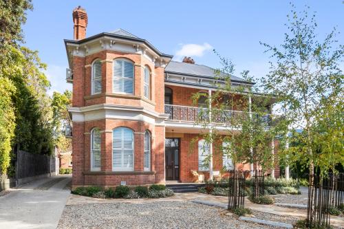 a red brick house with a balcony on it at The Rivulet in Hobart