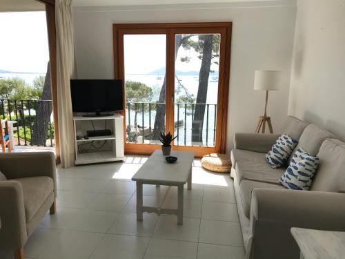a living room with a couch and a tv at Port Pollensa Pins Apartment sea view in Port de Pollensa