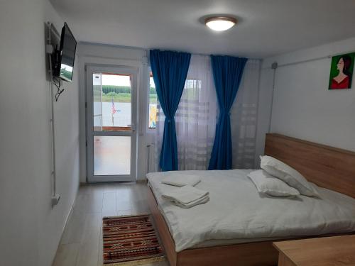 a bedroom with a bed with blue curtains and a window at Casa Antonia si Maria in Ostrov