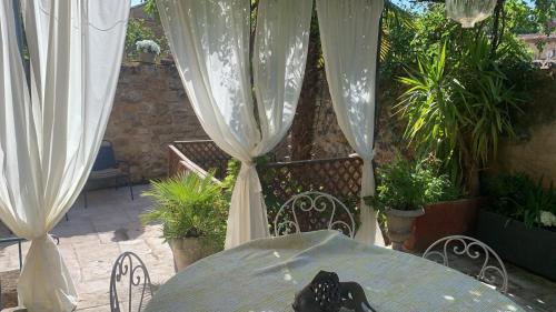 a table and chairs with white curtains on a patio at la villageoise, chambre troglodyte pitoresque au cœur du village in Rognes