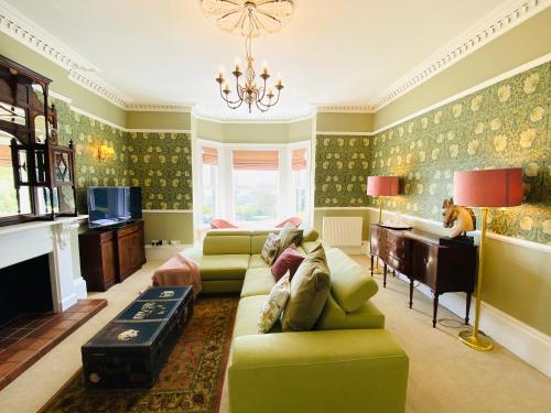 a living room with green furniture and a chandelier at Clarendon View, Historic Apartment with Sea Views in Ventnor